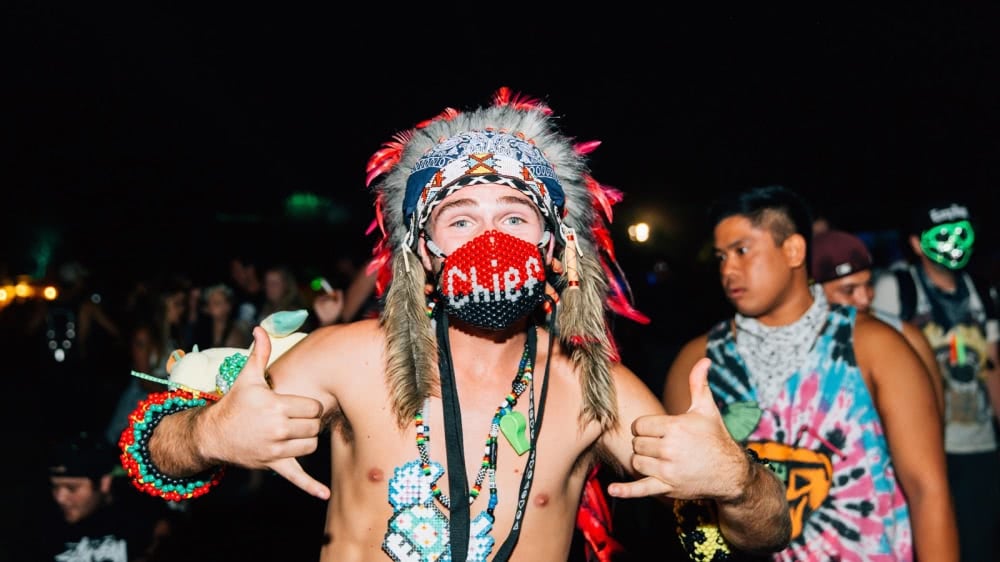 A man at a festival wearing a Native American headdress